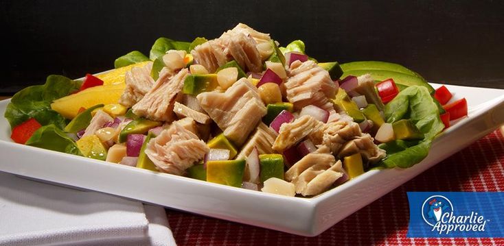 a white plate topped with chicken and veggies on top of a red checkered table cloth