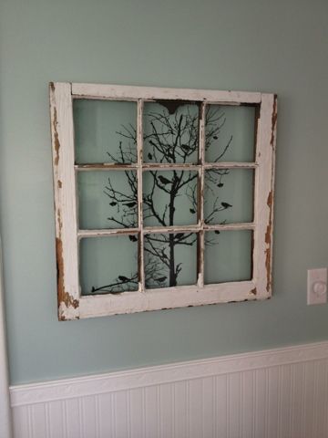 an old window is decorated with branches in the shape of a tree and birds on it