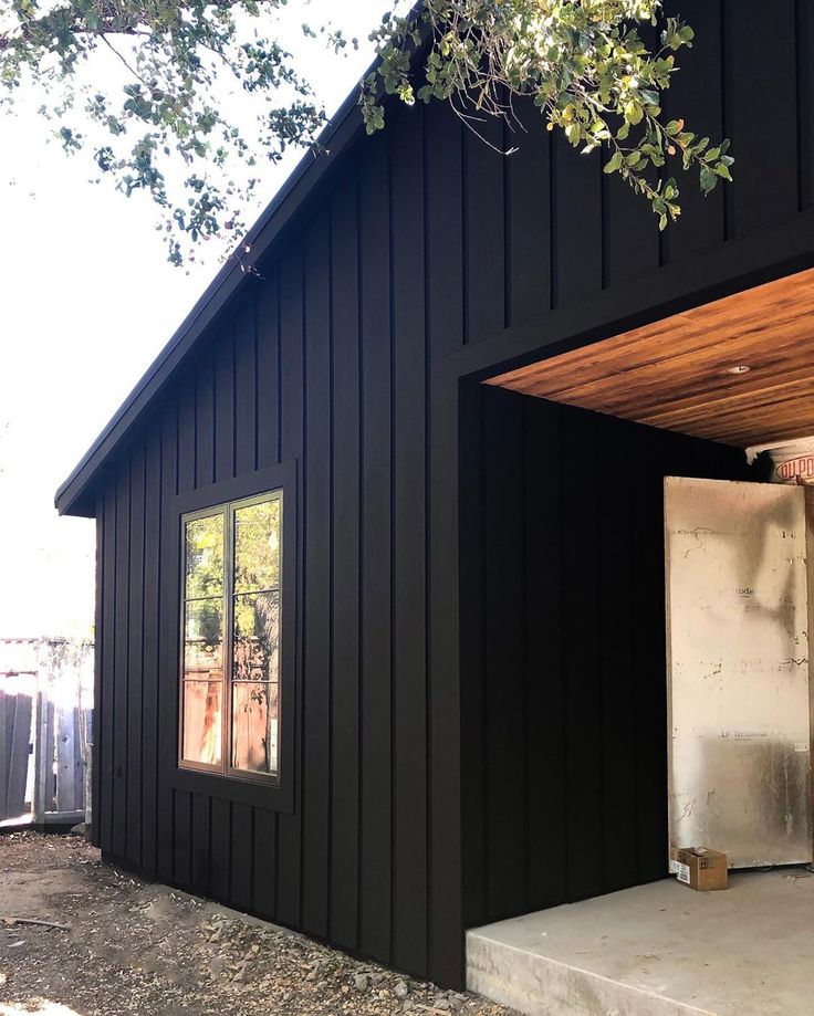 a small black house with a door open