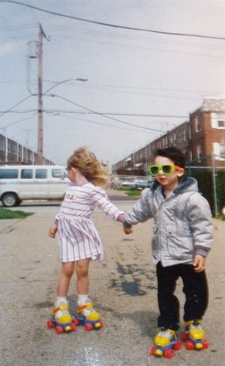 two young children holding hands while standing on roller skates in the middle of a street