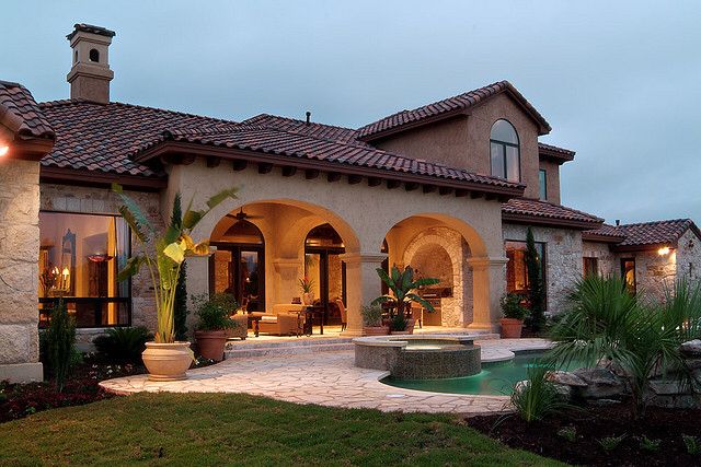 a large house with a pool in the front yard and landscaping around it at dusk