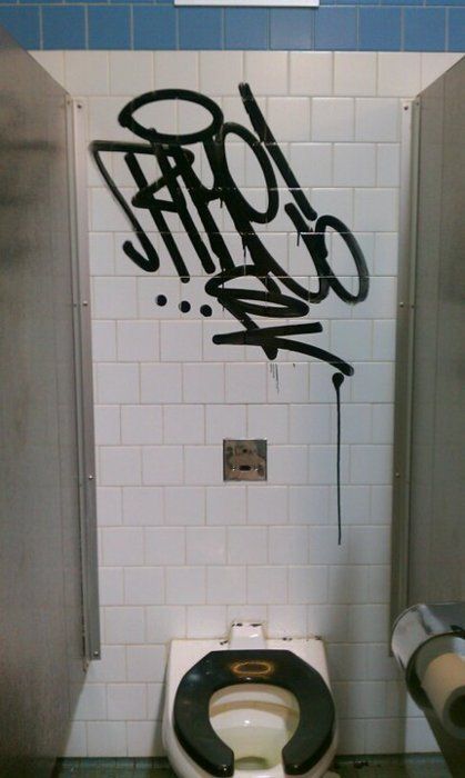 graffiti is spray painted on the wall next to a toilet in a public bathroom stall