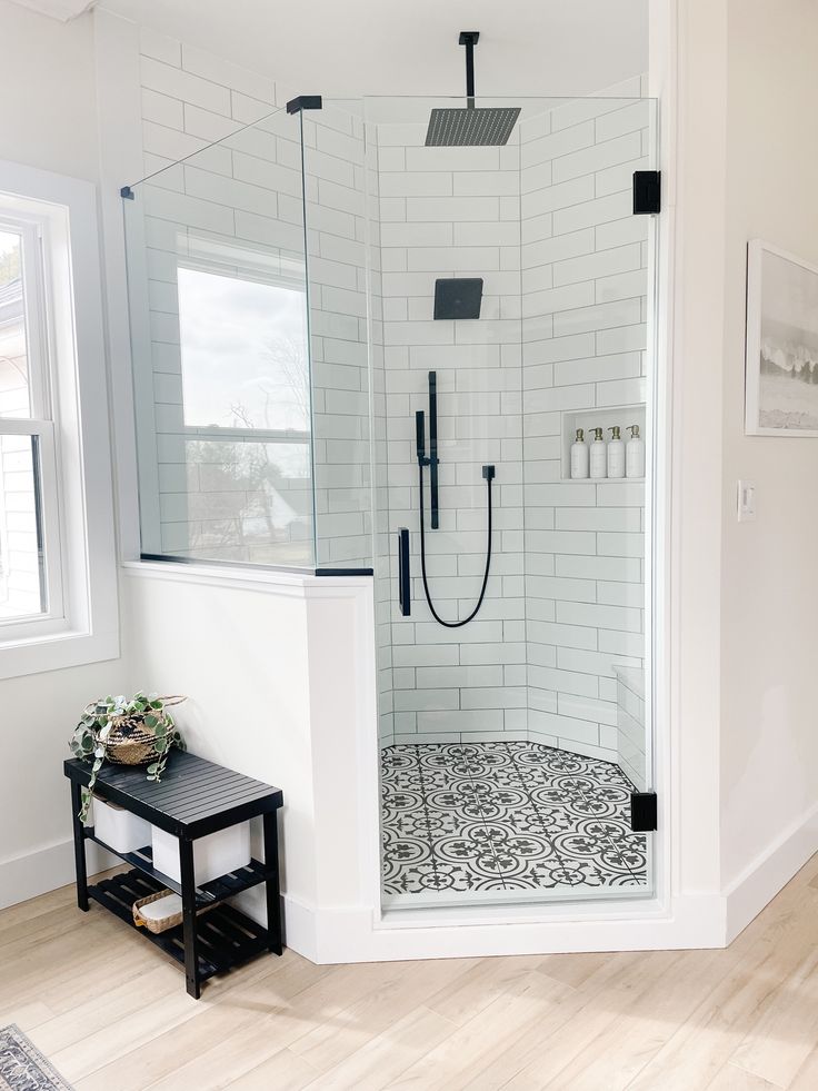 a bathroom with a walk in shower next to a white wall and wooden flooring