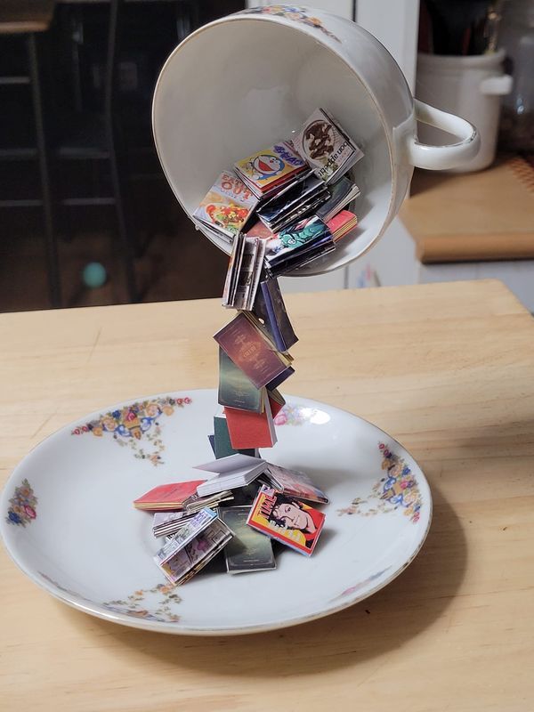 a teacup is filled with small cards on a plate that has been thrown into the air