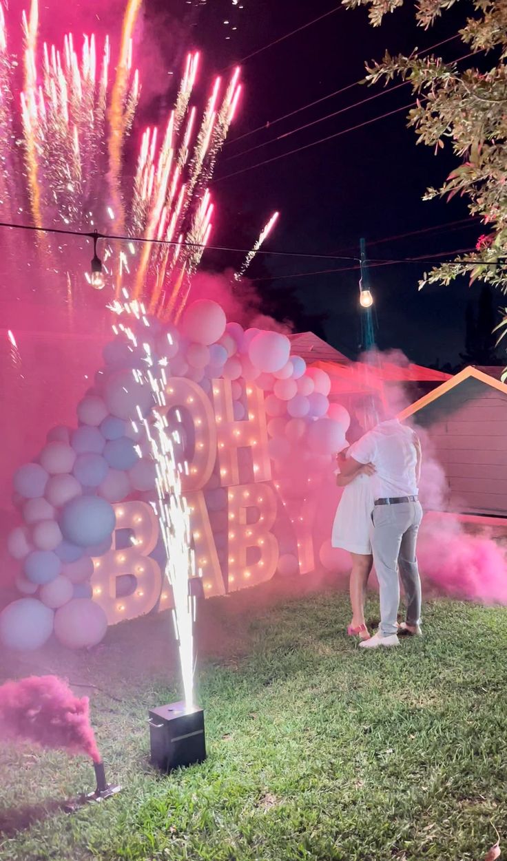 two people standing in front of a sign that says happy birthday with balloons and streamers