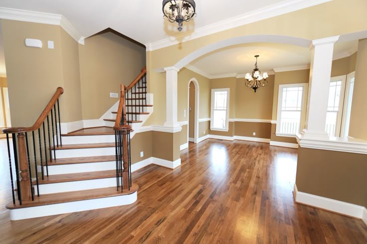 an empty living room with hard wood floors and white trim on the walls, and stairs leading up to the second floor