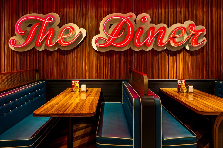 the diner is decorated with neon signs and wood booths, along with blue leather seats