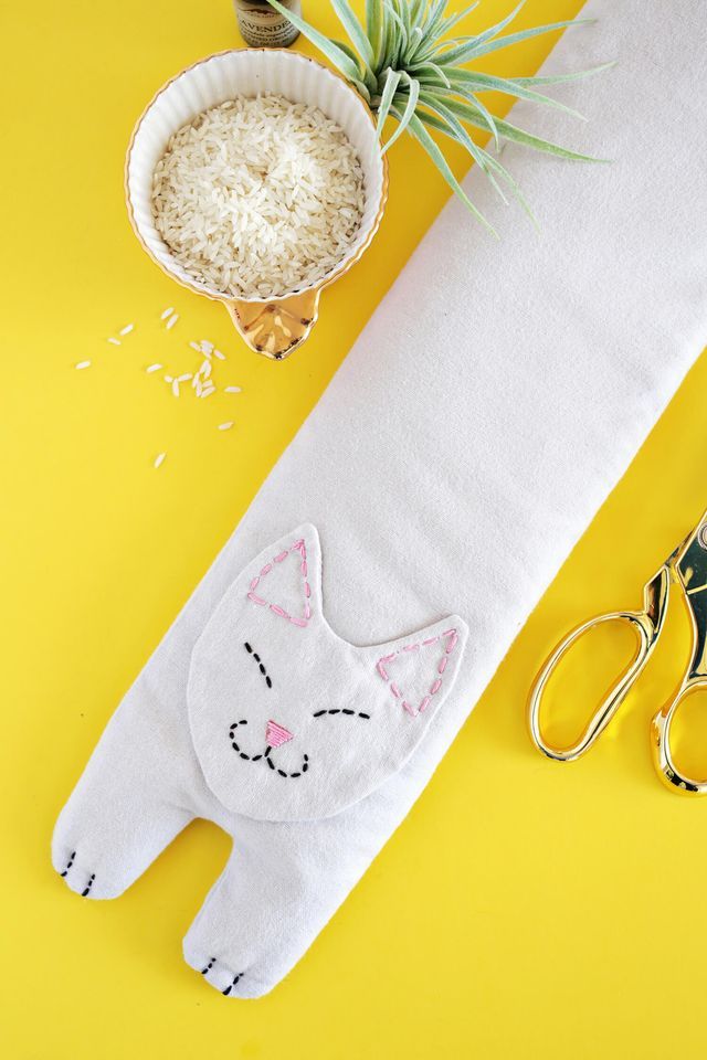 a pair of scissors sitting next to a white cat pillow on top of a yellow table