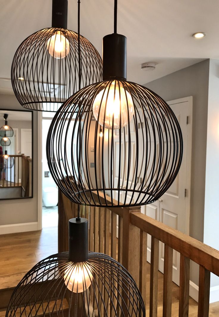 three light fixtures hanging from a wooden railing