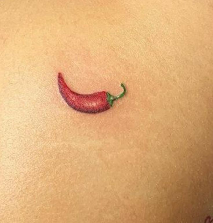 a red chili pepper tattoo on the back of a woman's left side ribcage