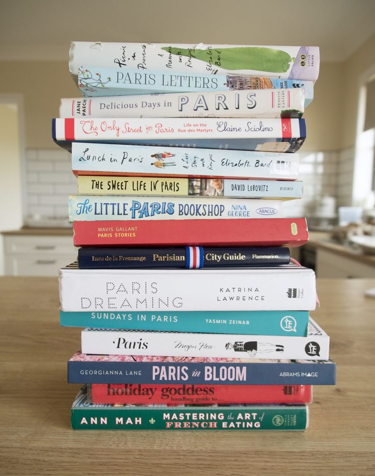 a stack of books sitting on top of a wooden table in front of a kitchen