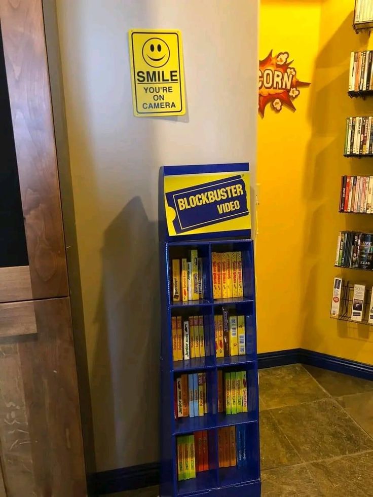 there is a blue book stand with books on it in front of a yellow wall