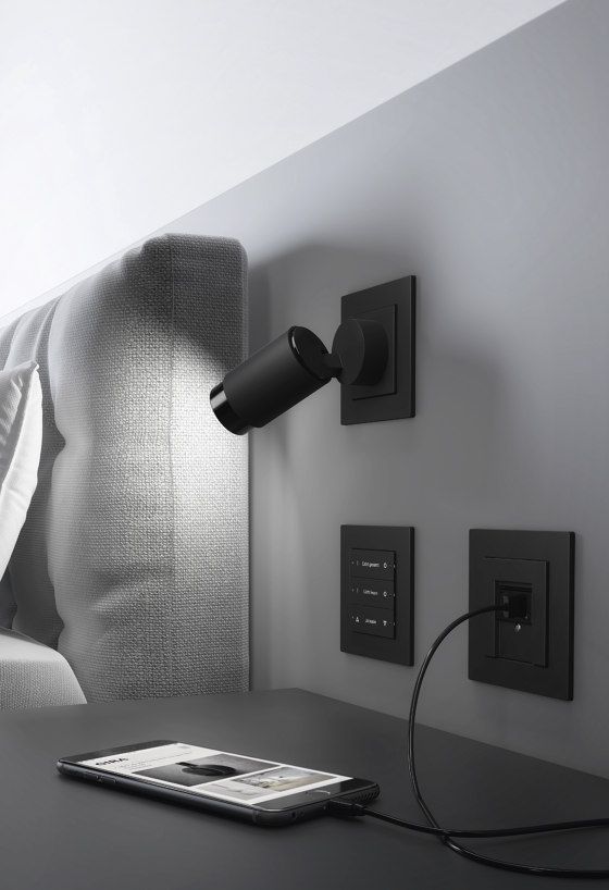 an electronic device is plugged into a wall light on the side of a bed