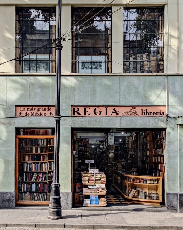 a street corner with books on display in front of a building that reads regla libera