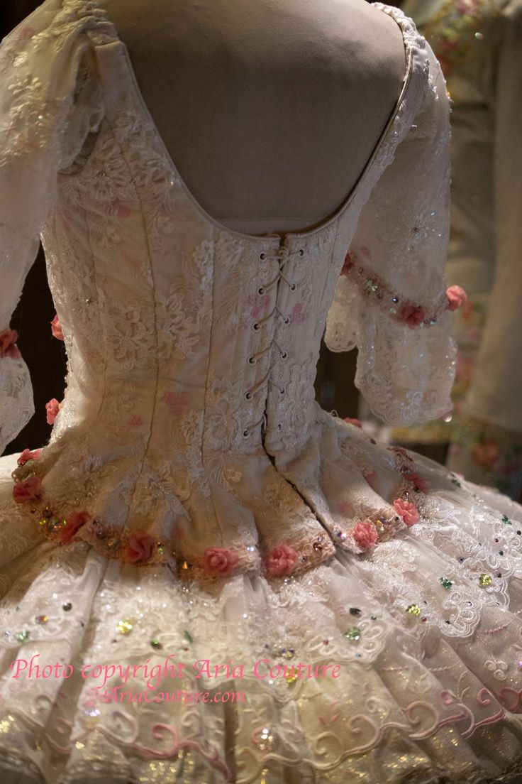 the back of a white dress with pink flowers on it's skirt and sleeves