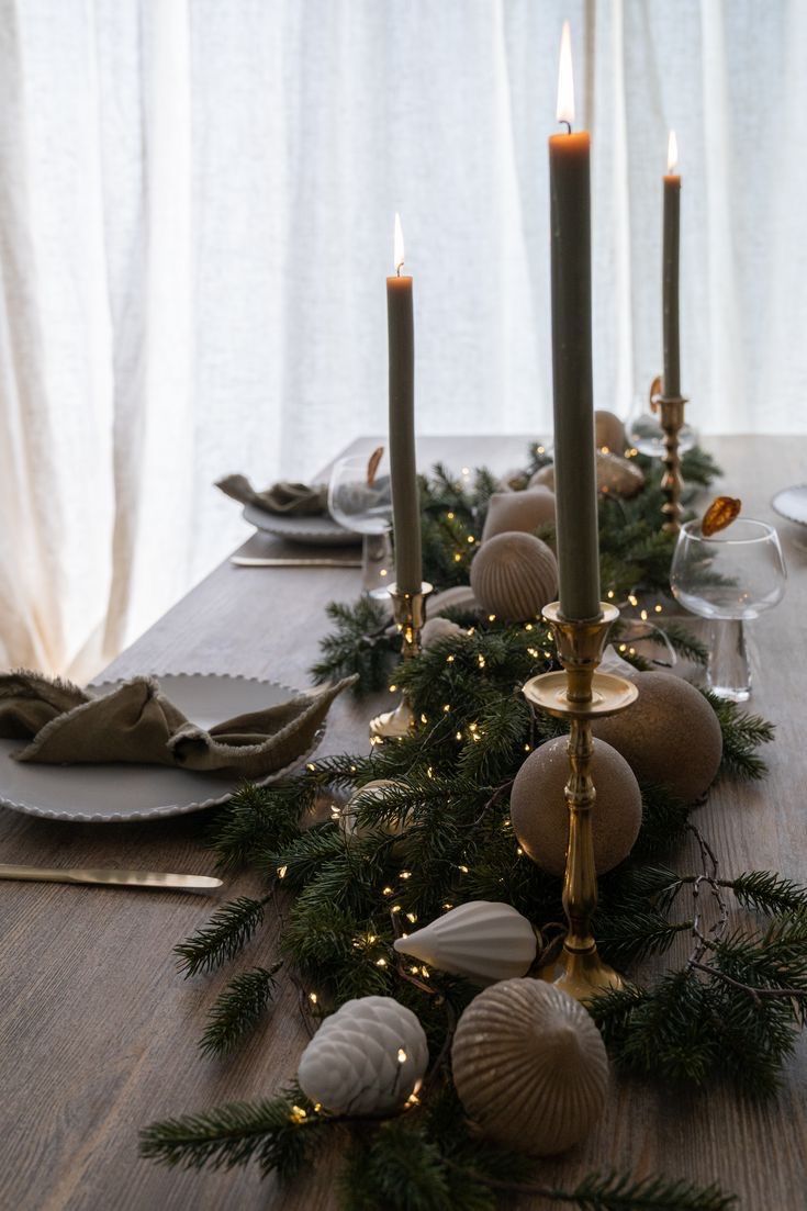 a long table with candles, plates and napkins on it is decorated for christmas