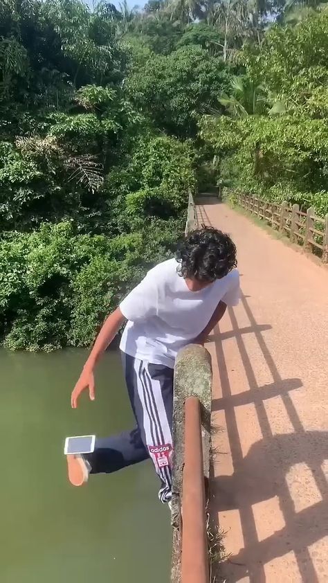 a man is jumping off a bridge into the water with his feet in the air