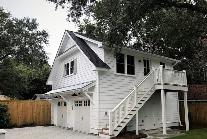 a two story white house with stairs leading up to it