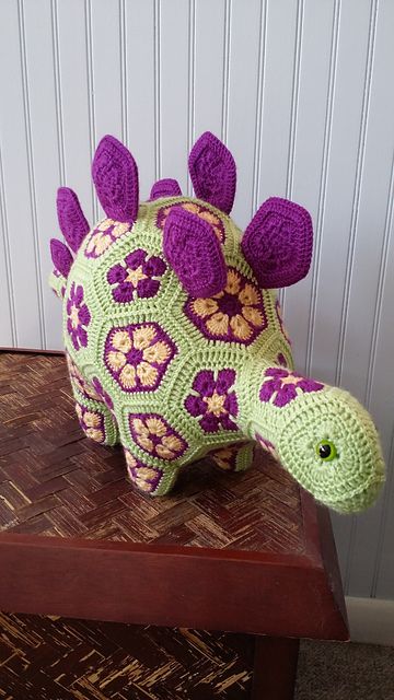 a crocheted stuffed animal sitting on top of a wooden table next to a wall