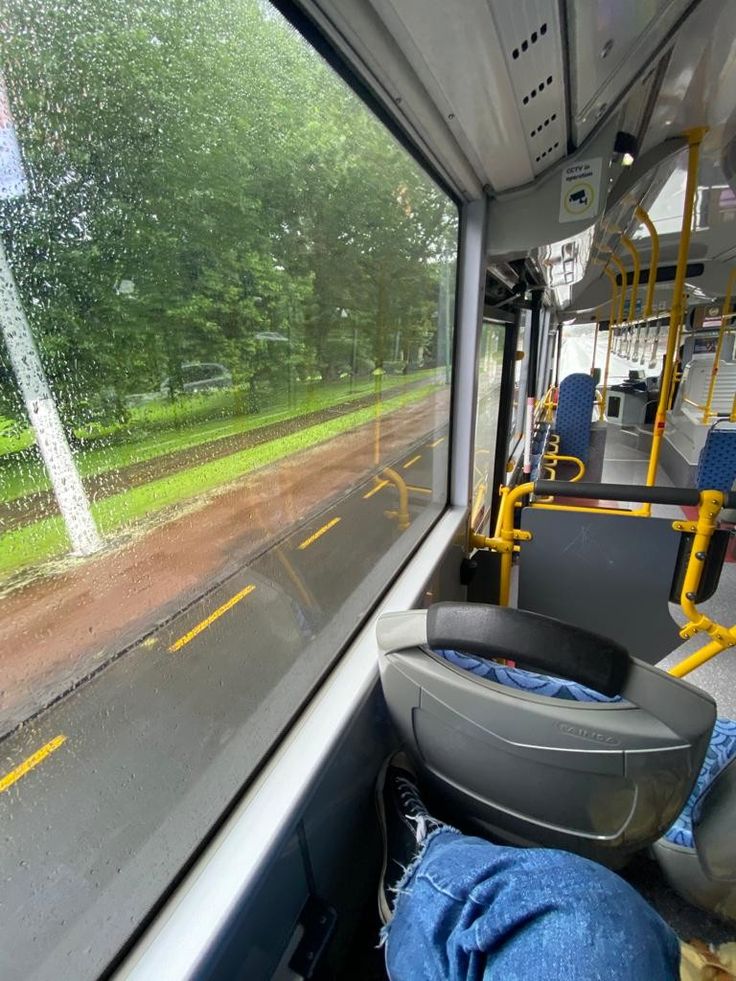 the inside of a bus with blue jeans on it and trees in the back ground