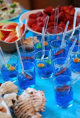 a table topped with plates and cups filled with blue liquid next to other food items