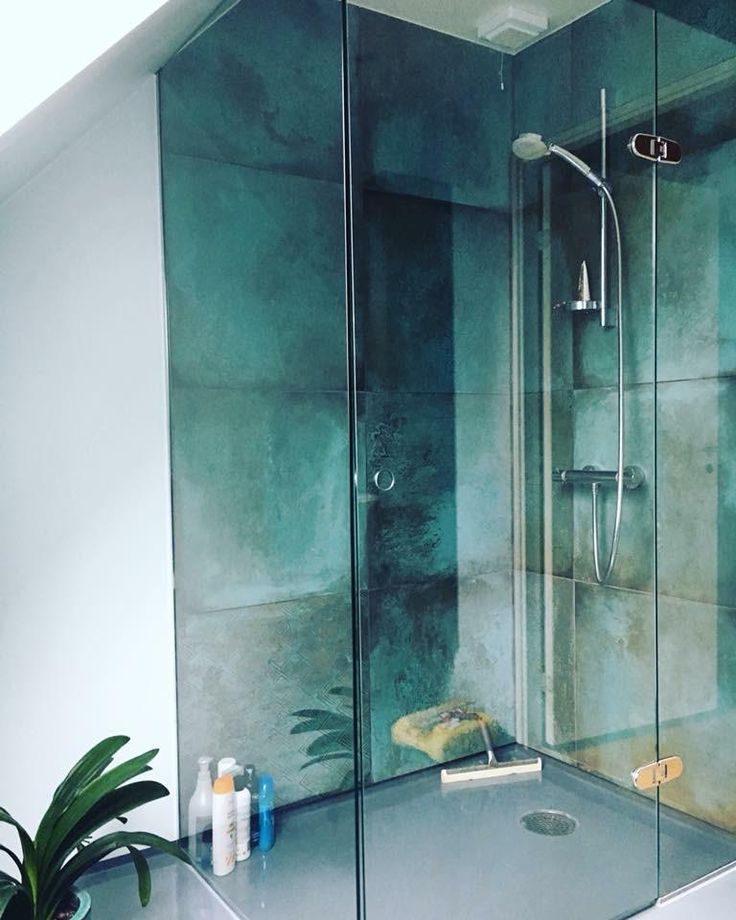 a bathroom with a glass shower door and green walls