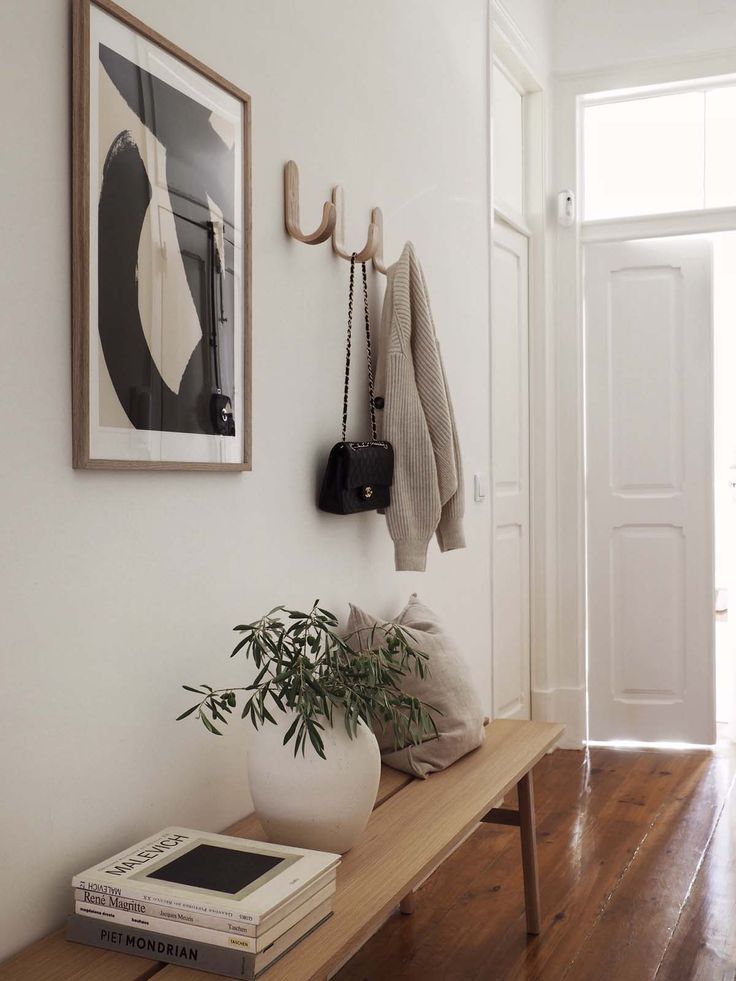 a white entryway with a wooden bench and potted plant on the shelf next to it