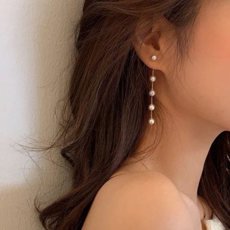 a close up of a person wearing some kind of earring with pearls on it