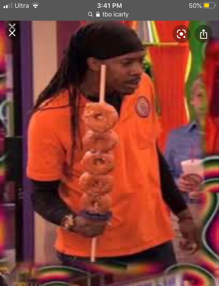 a man with dreadlocks holding a donut on a stick in front of him