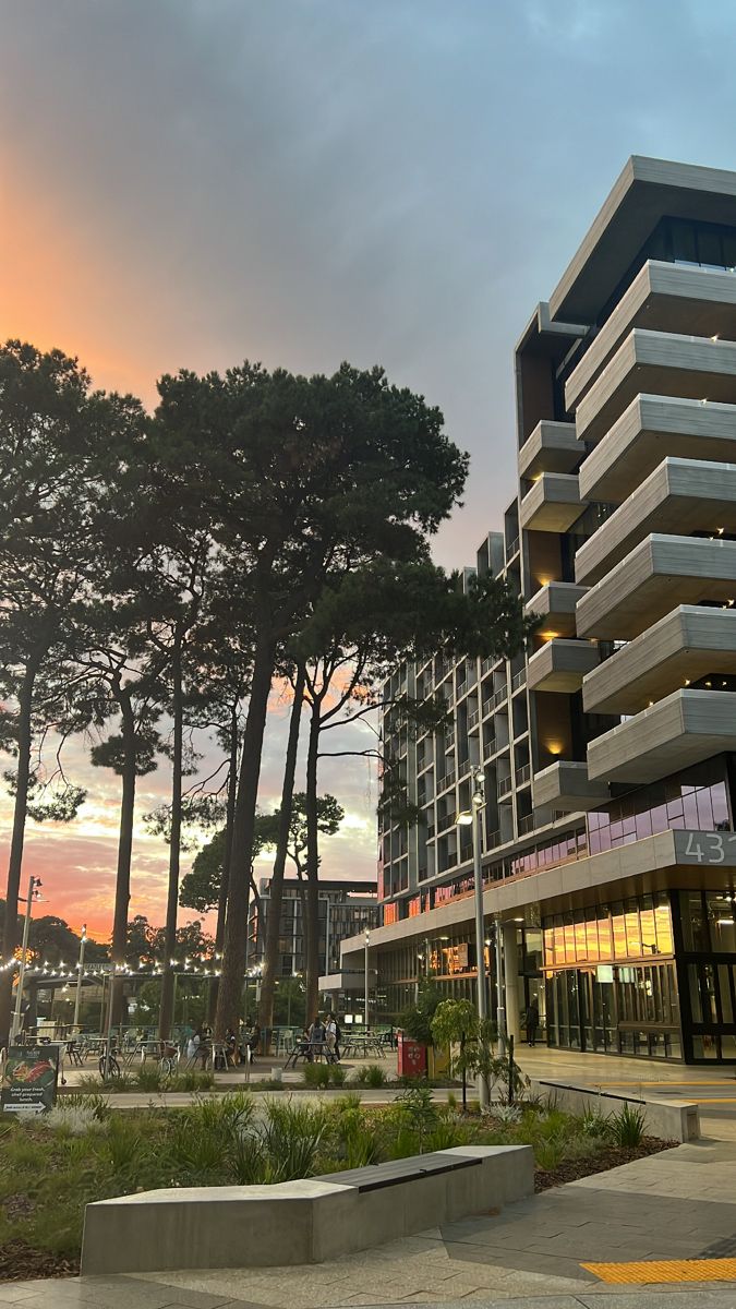 an apartment building with many balconies and trees in the foreground at sunset