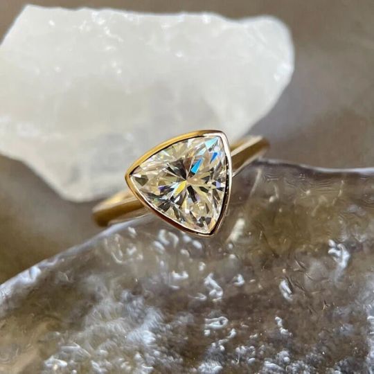 a yellow diamond ring sitting on top of a rock