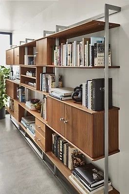 a bookshelf filled with lots of books next to a plant in a room