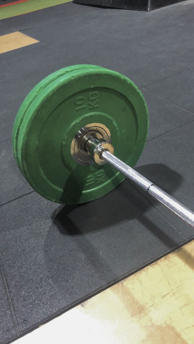 a green barbell on the ground in a gym