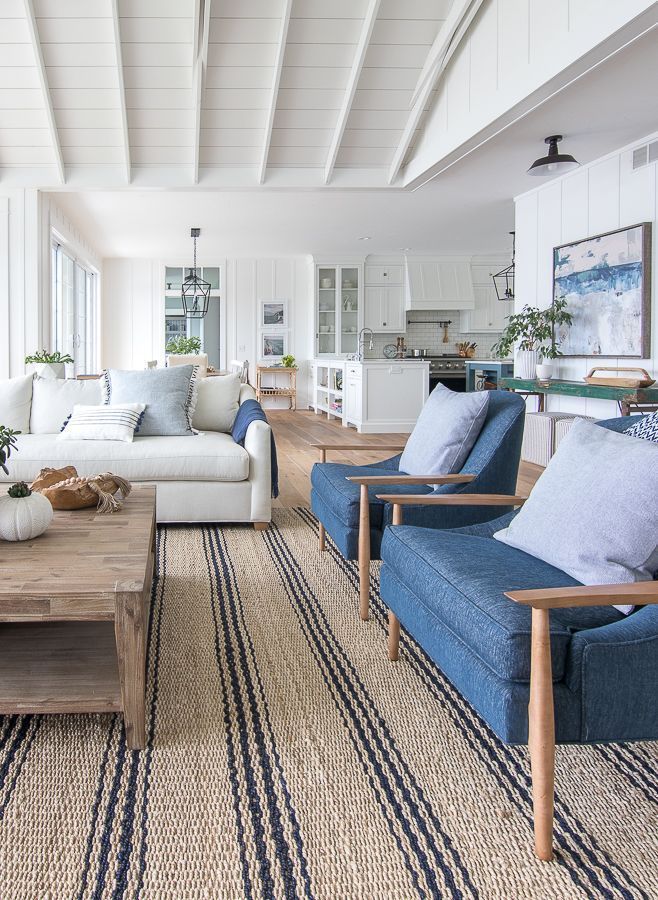 a living room with couches, chairs and rugs in front of large windows