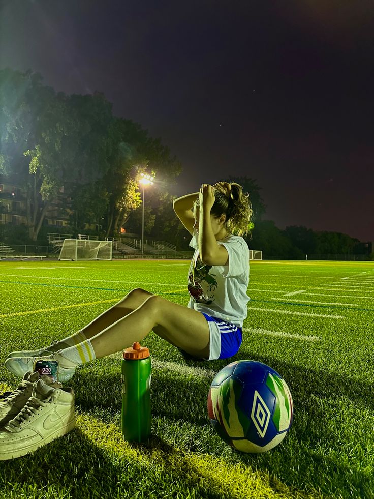 a woman sitting on the ground next to a soccer ball