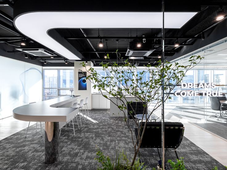 an office with white walls and black ceilinging, plants in the middle of the room