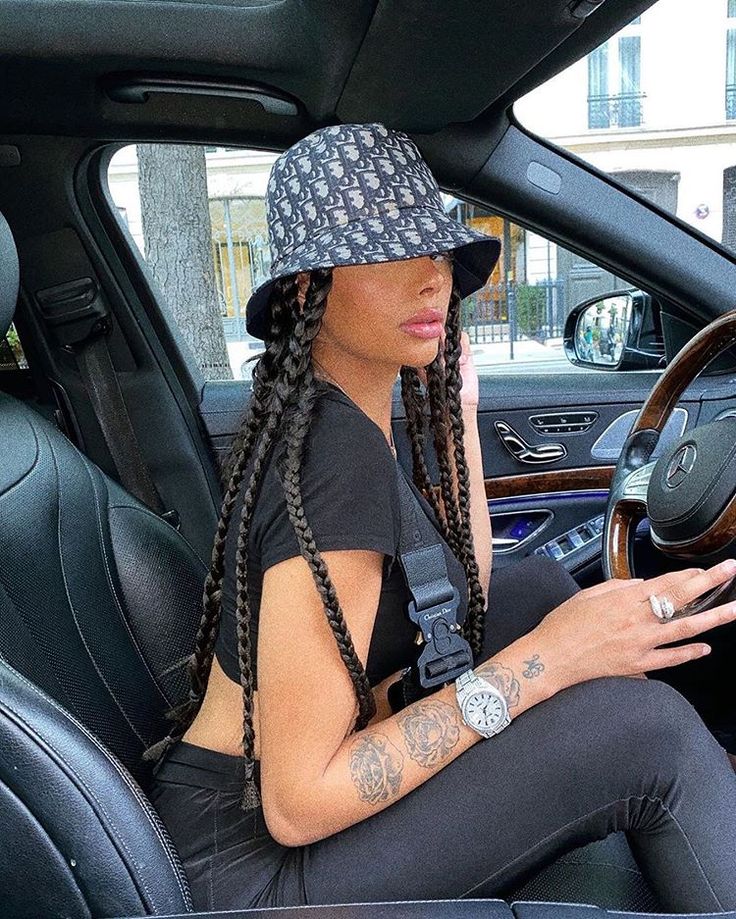 a woman sitting in the driver's seat of a car while holding a cell phone