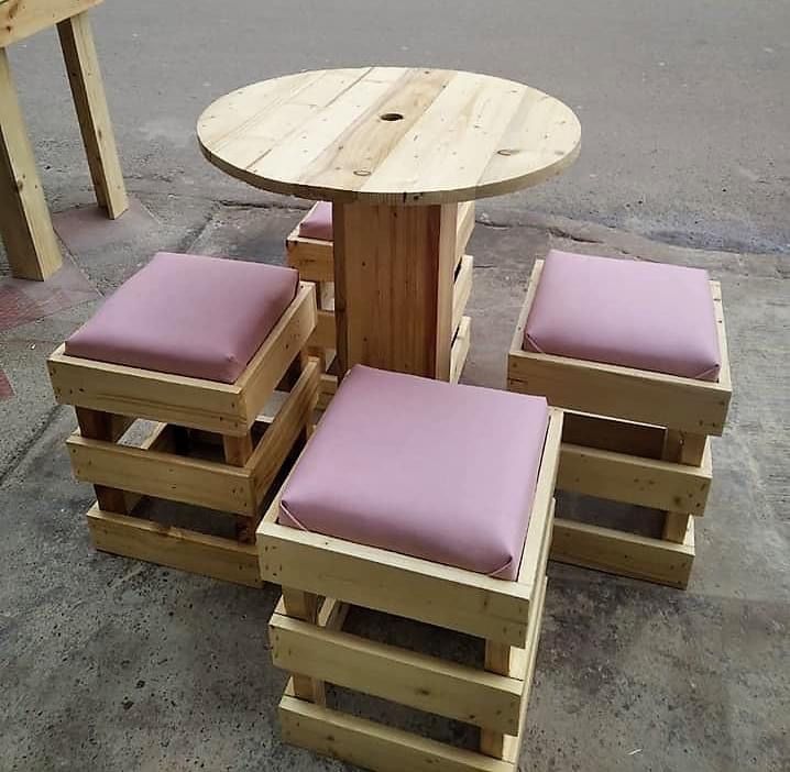 a wooden table and chairs made out of pallet wood with pink cushions on them