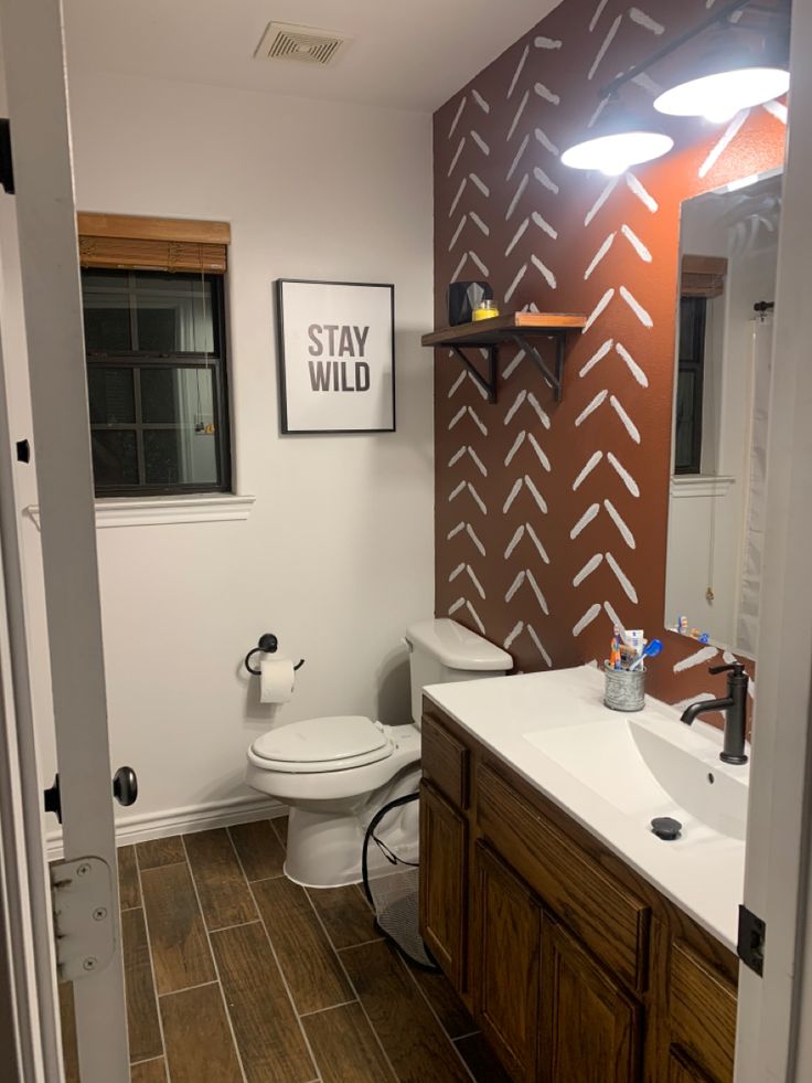 a bathroom with a toilet, sink and mirror next to a wall that has arrows painted on it