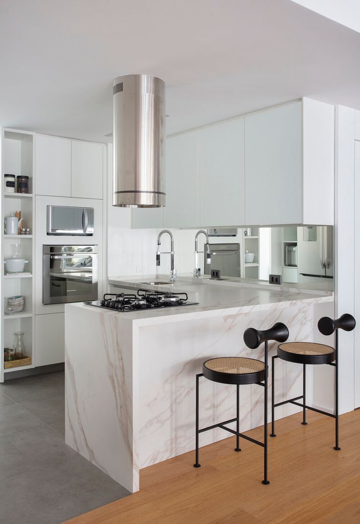 two stools sit in front of an island counter with a stove and oven on it