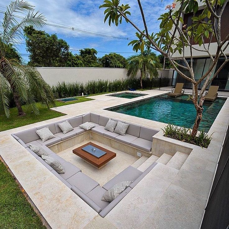 a couch sitting on top of a lush green field next to a swimming pool