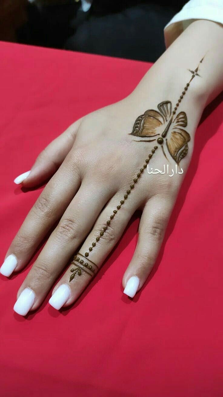 a woman's hand with henna tattoos on her left wrist and fingers, sitting on a red table