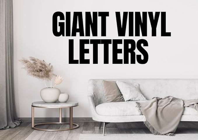 a living room with a white couch and black lettering on the wall that says giant vinyl letters