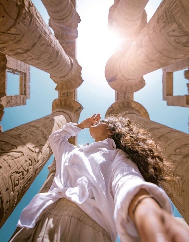 a woman is standing in front of the sun with her hands up to her face