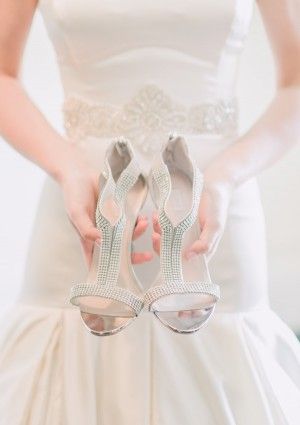 the bride is holding her wedding shoes in both hands and wearing them with their dress