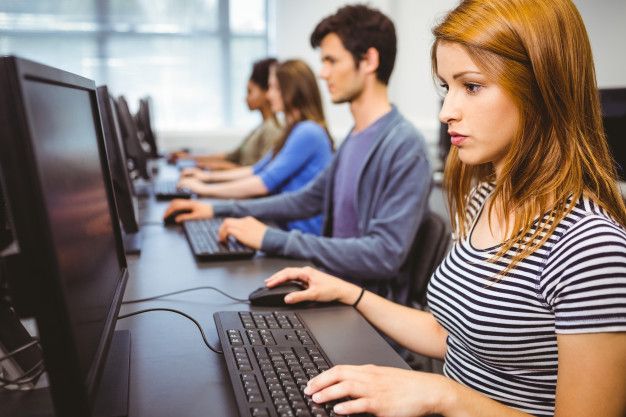 a group of people working on computers in an office setting with one woman using the computer