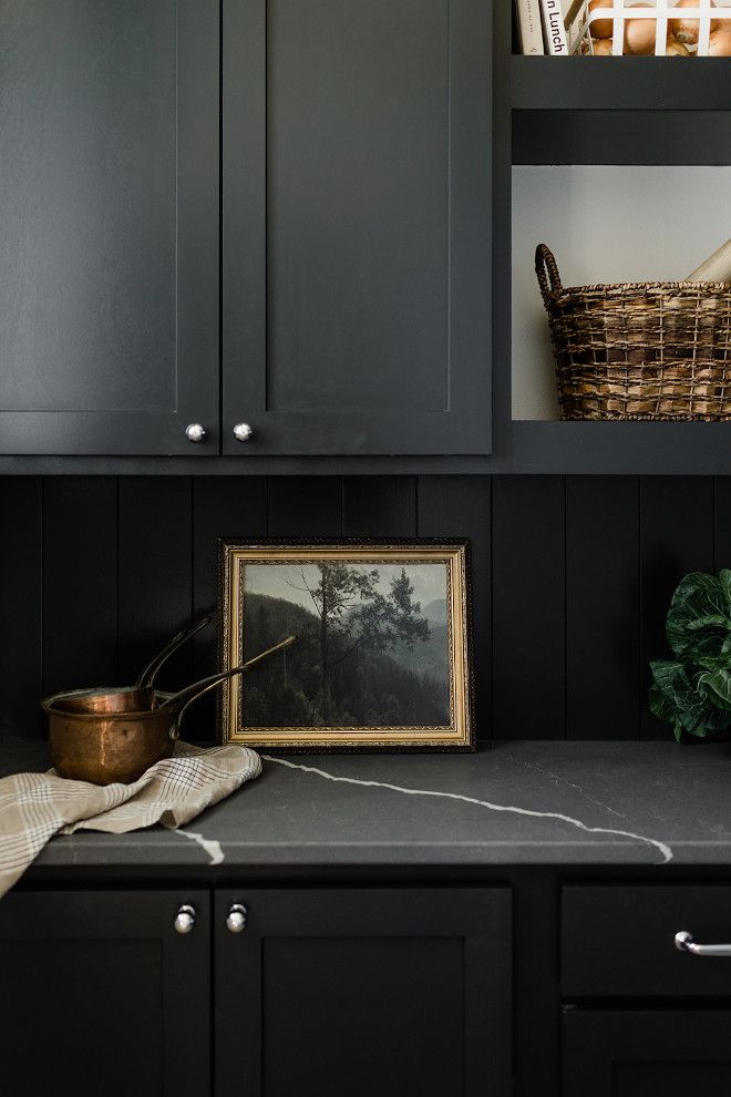 a kitchen with black cupboards and a basket on the counter top in front of it