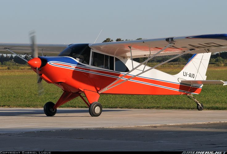 an orange and blue plane is on the runway with grass in the backround