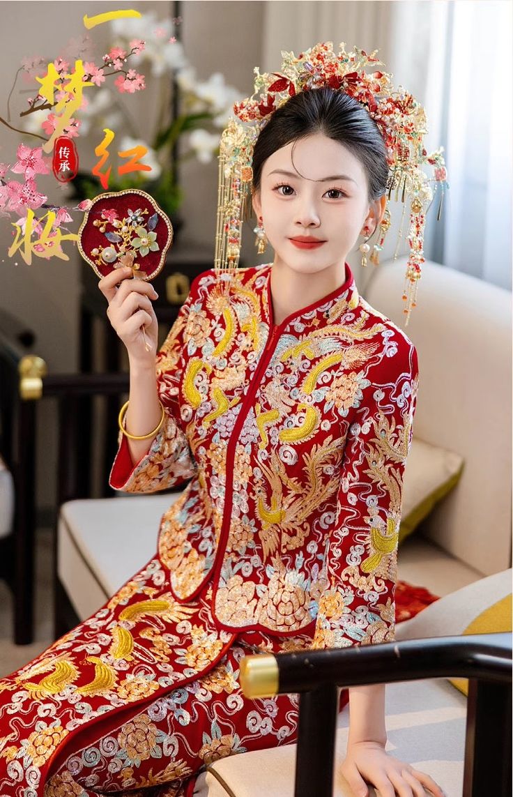 a woman in a red and gold chinese dress holding a fan with flowers on it