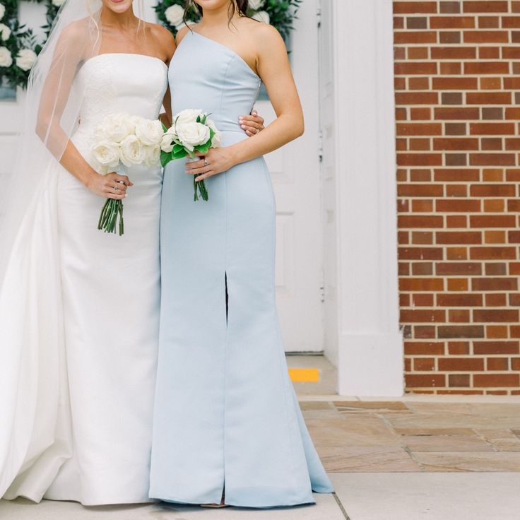 two bridesmaids pose for a photo in front of the church door with their bouquets